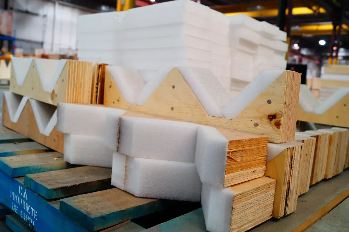 Foam lined wooden corner protectors arranged on a pallet in a warehouse.