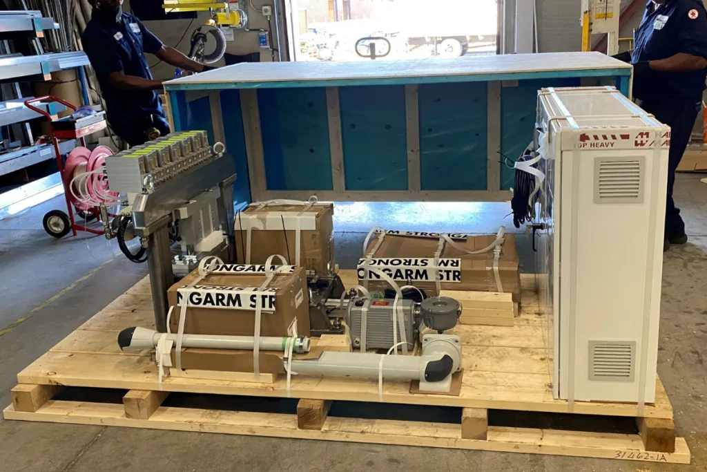 Industrial components and boxes secured to a custom wooden skid, ready for crating.